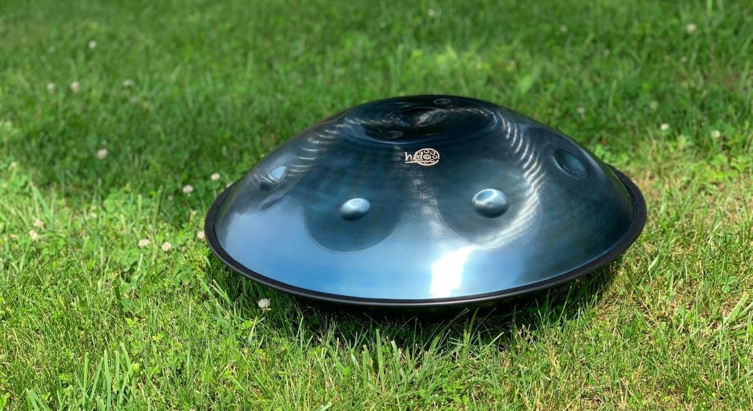 A blue handpan resting on grass