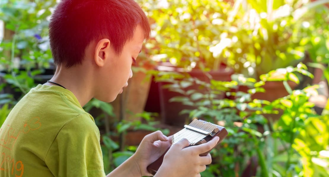 A boy playing a wooden kalimba