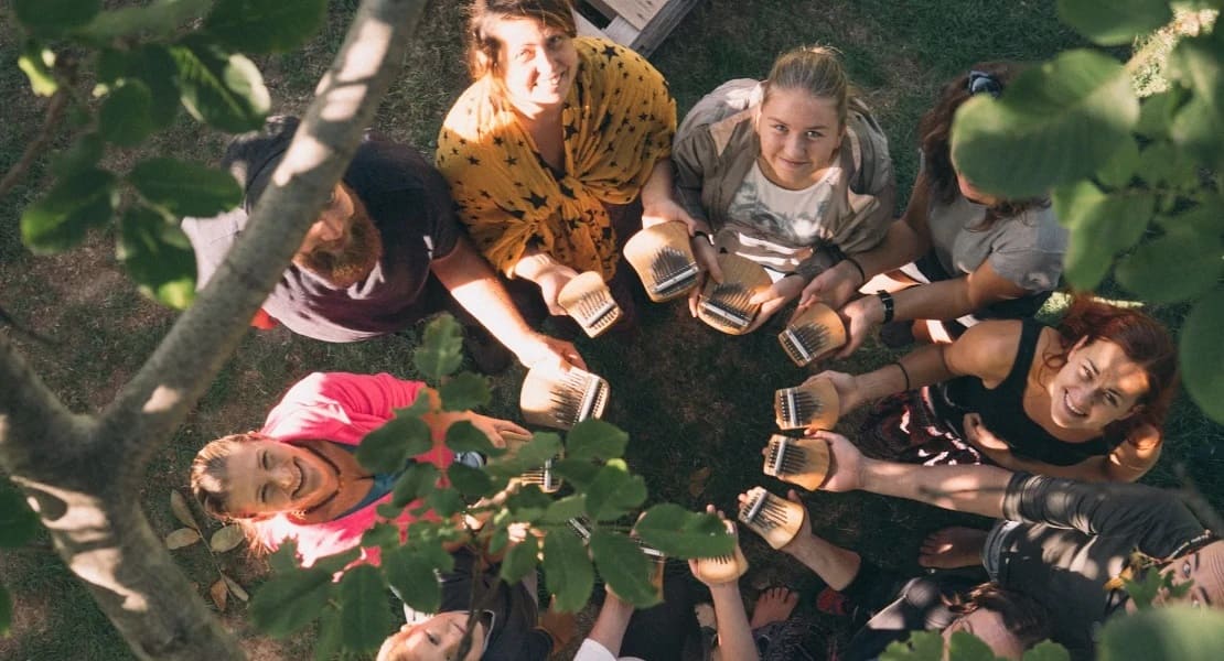 A circle of people seen from above, all holding a kalimba