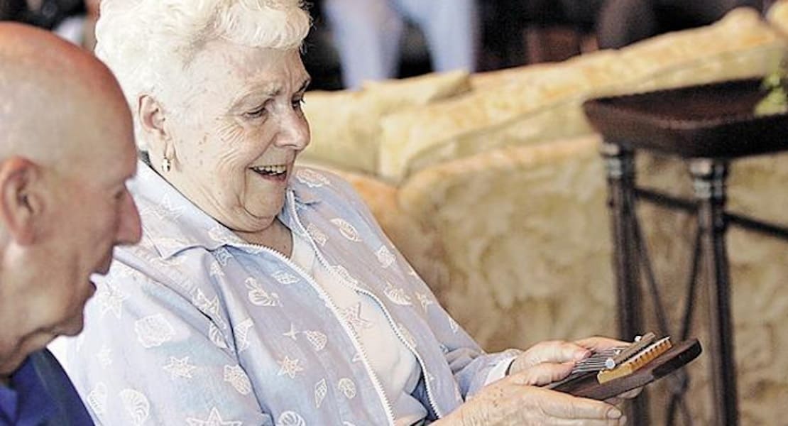 An elderly person playing a kalimba