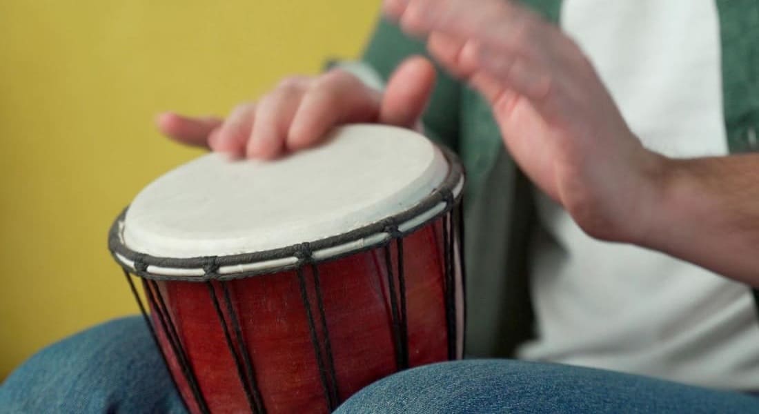 A person playing a red djembe
