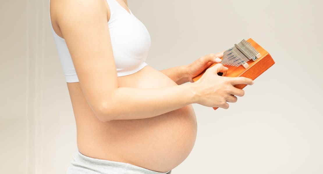 A pregnant woman playing a kalimba