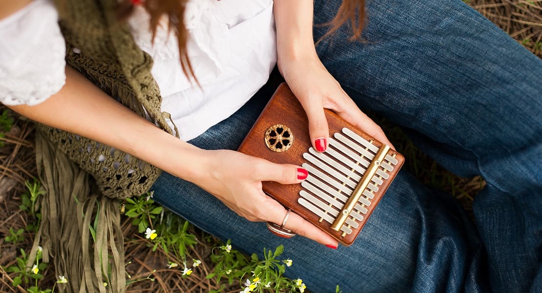 A seated woman playing a wooden kalimba