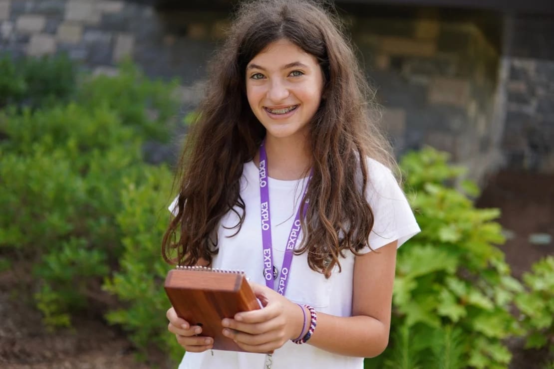 A smiling teenage girl holding a kalimba