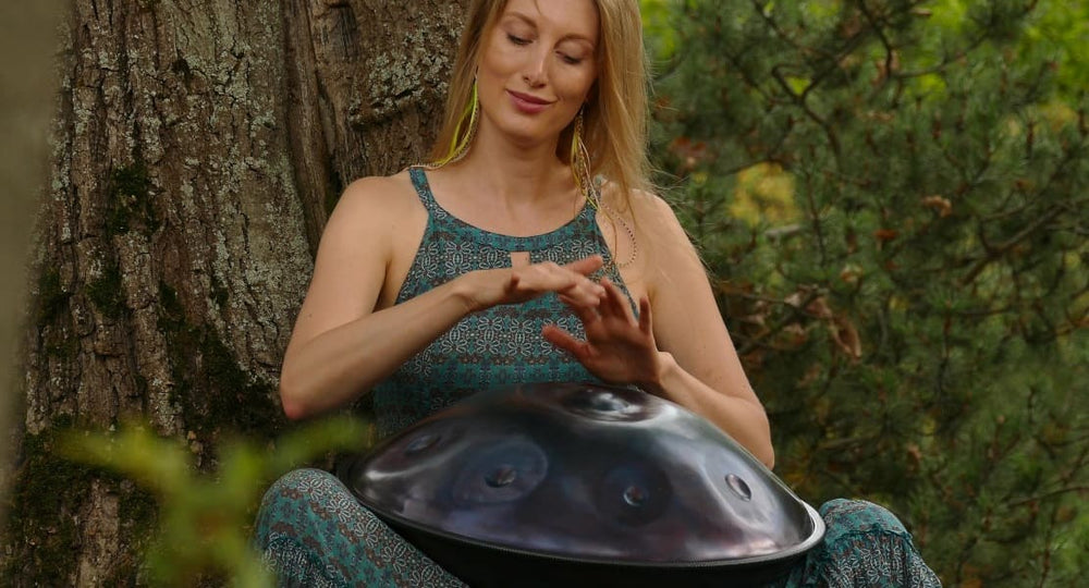 A woman in the forest playing a handpan