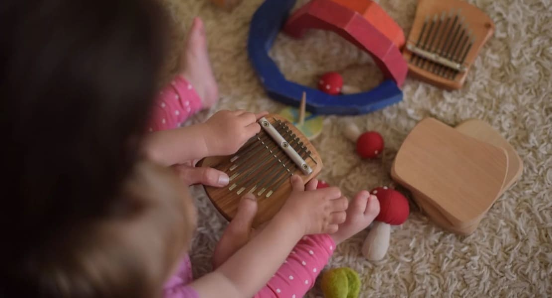 A woman playing a kalimba with her baby
