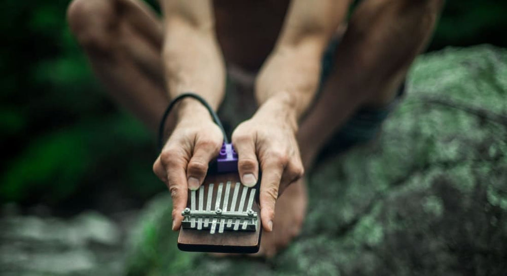 An Aboriginal person playing kalimba in the forest