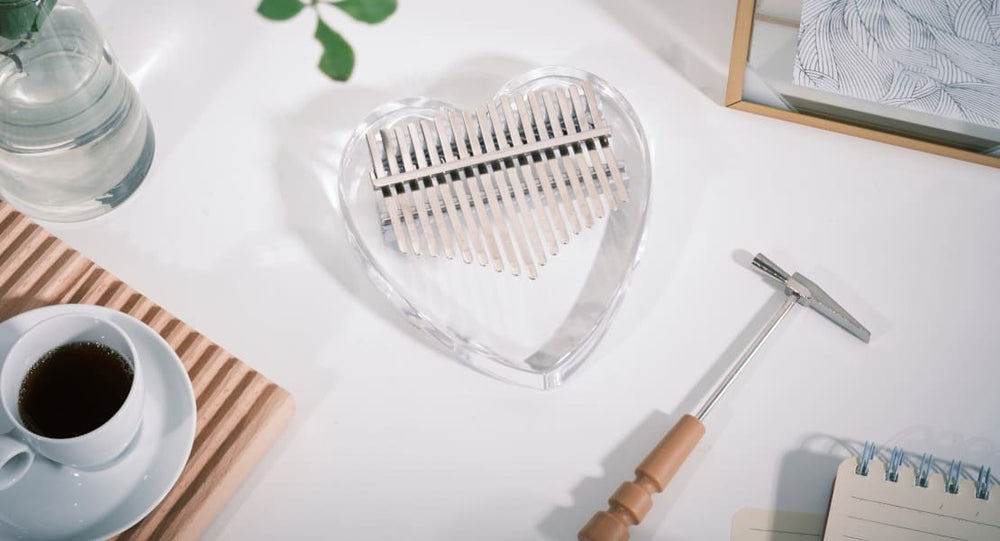 An acrylic kalimba on a table with its tuning hammer