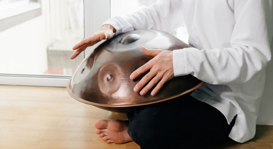 A barefoot man playing the handpan