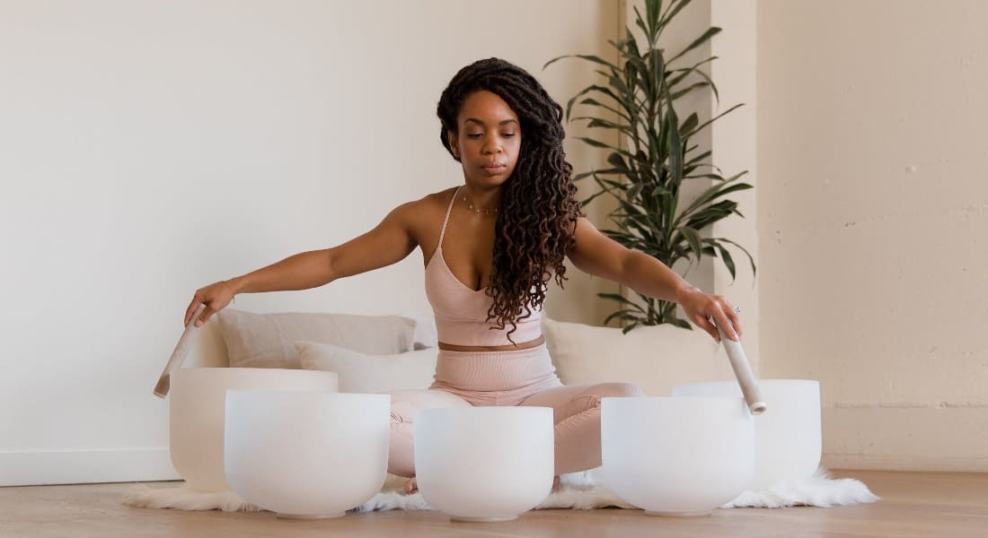 A Black woman using crystal singing bowls