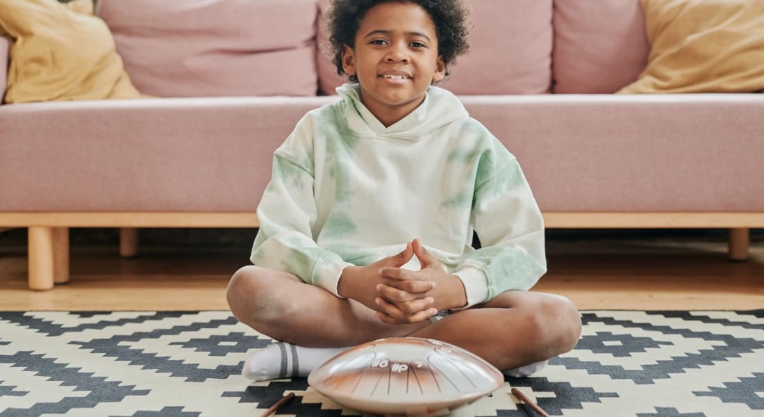 A child sitting in front of a tongue drum