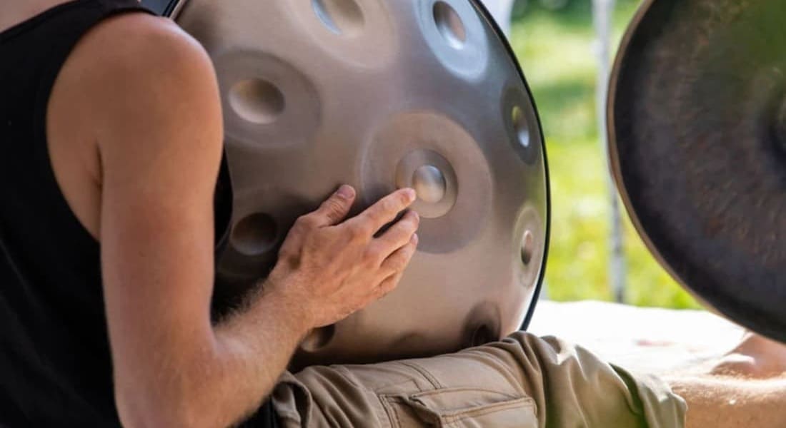 Close-up of a handpan player sitting on the floor holding his instrument