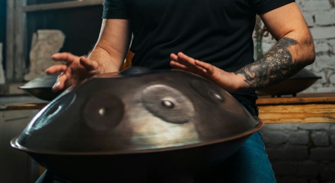 Close-up of a man playing a handpan in his lap