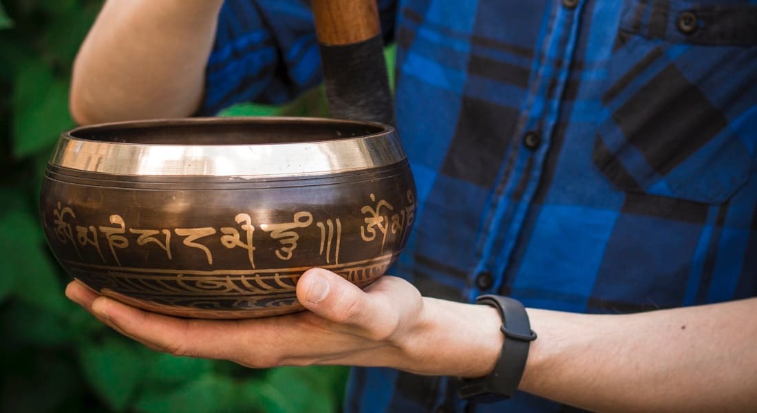 A close-up of a hand holding a Tibetan singing bowl