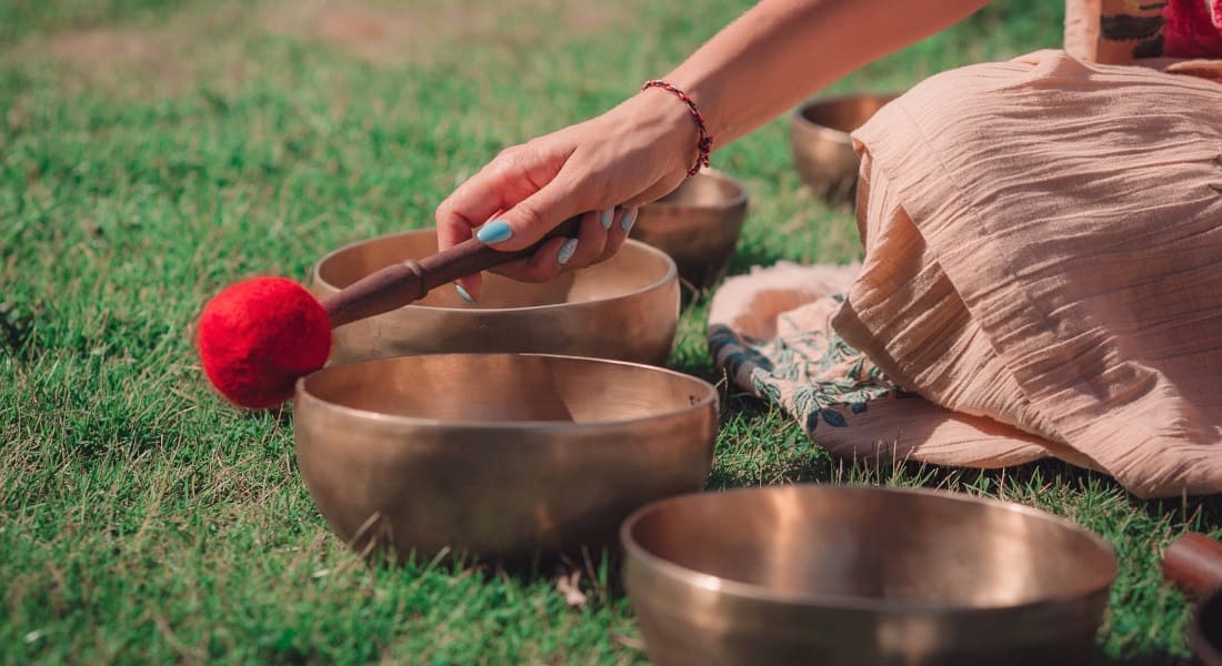 Close-up on a woman's hand holding a mallet with 4 singing bowls next to it