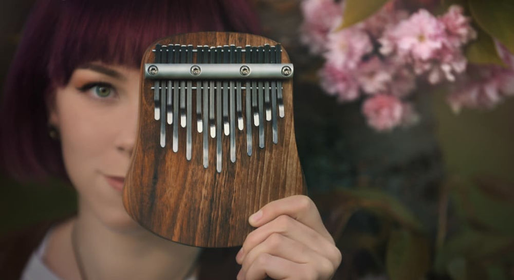 A close-up of a woman holding a kalimba in front of her face