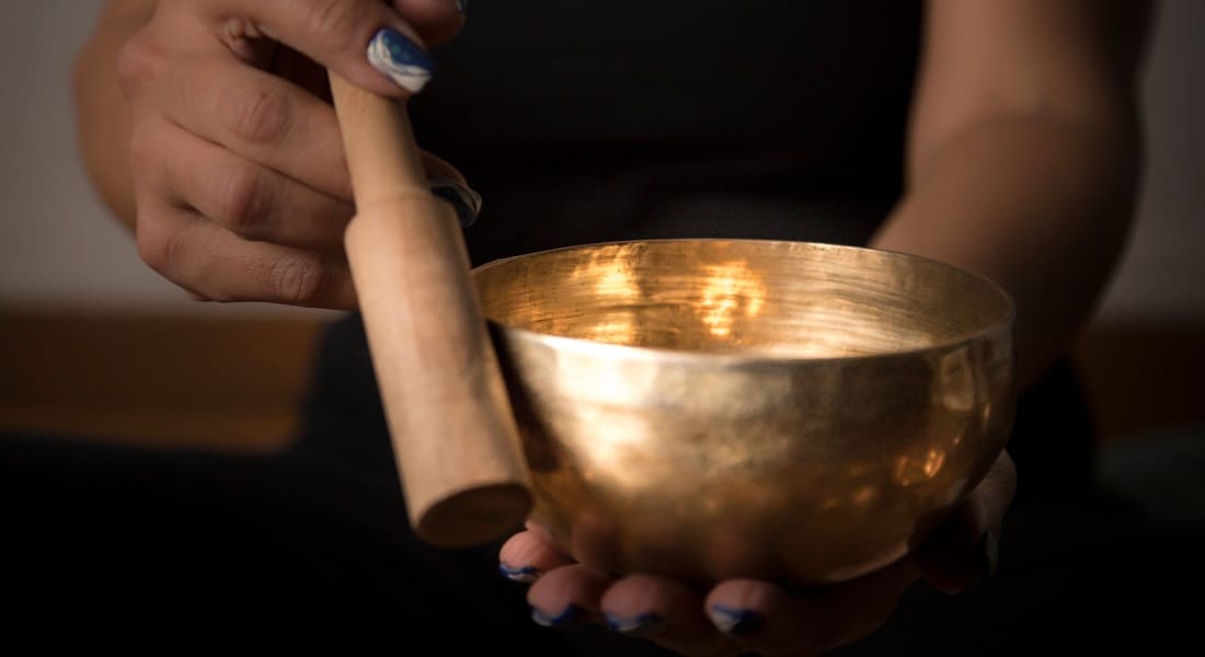 Close-up of a woman playing a Tibetan singing bowl