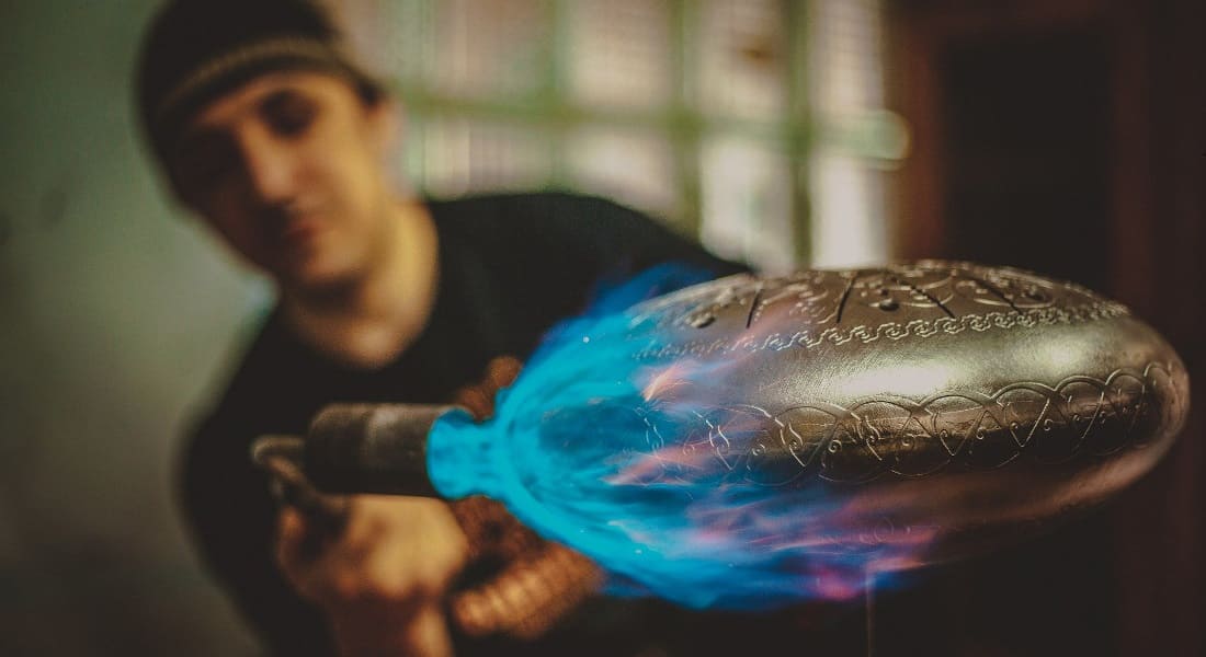 A craftsman welding the shells of a tongue drum