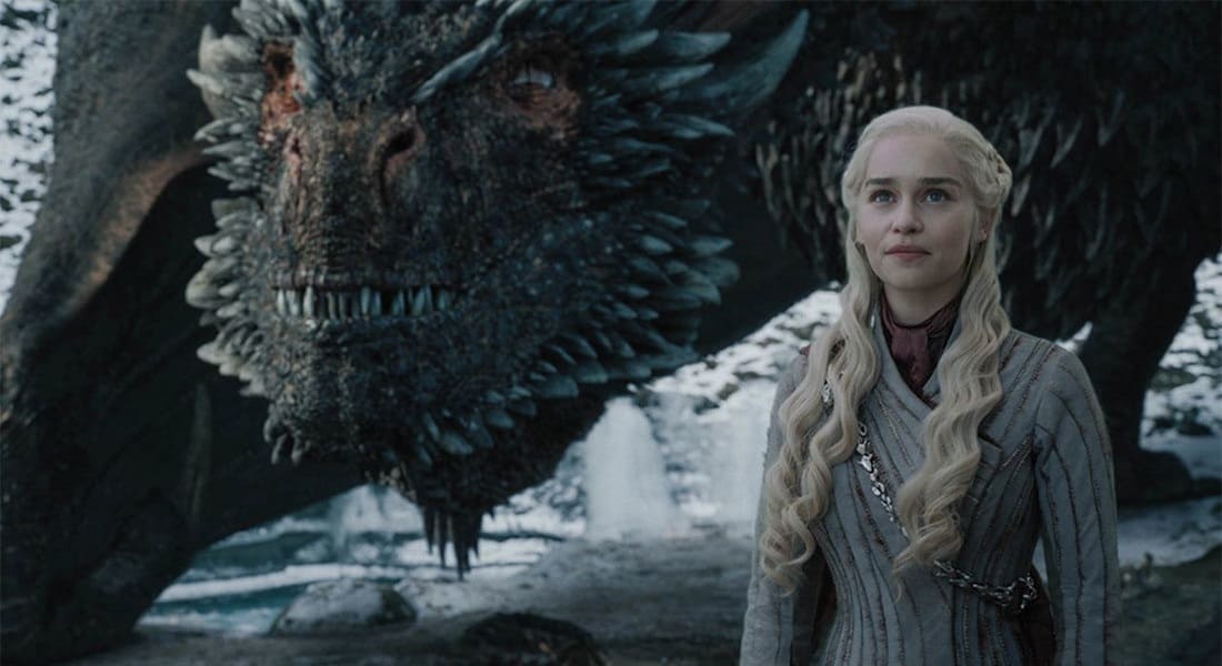 Daenerys Targaryen from the Game of Thrones series standing with one of her dragons in the background beside her