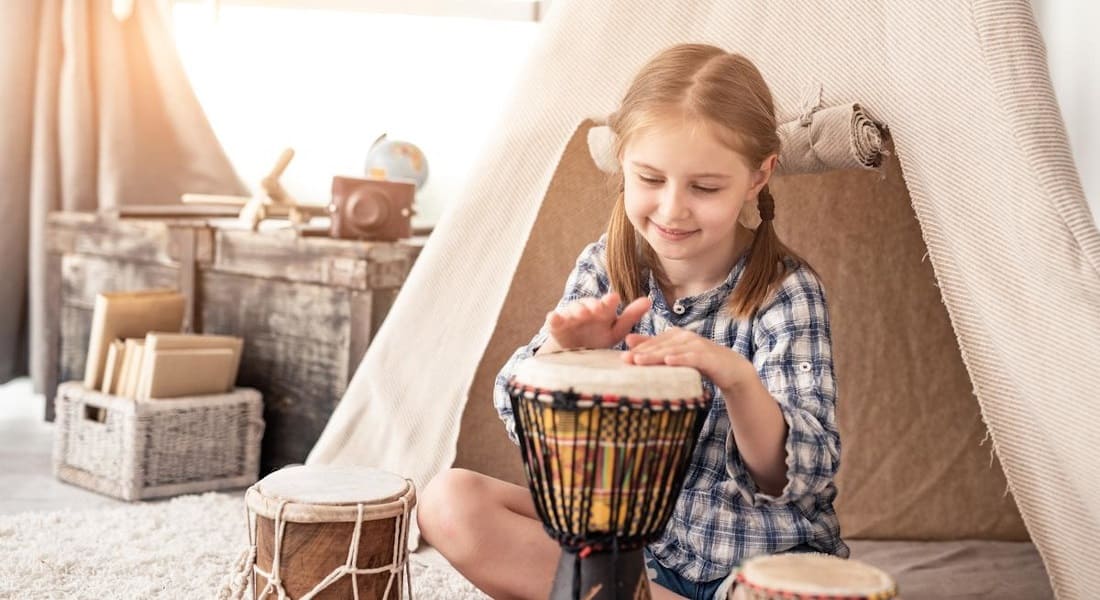 A girl playing a djembe in her bedroom