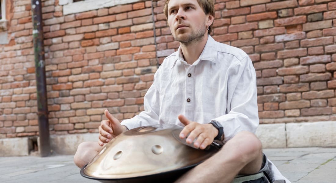 A handpan player sitting in the street
