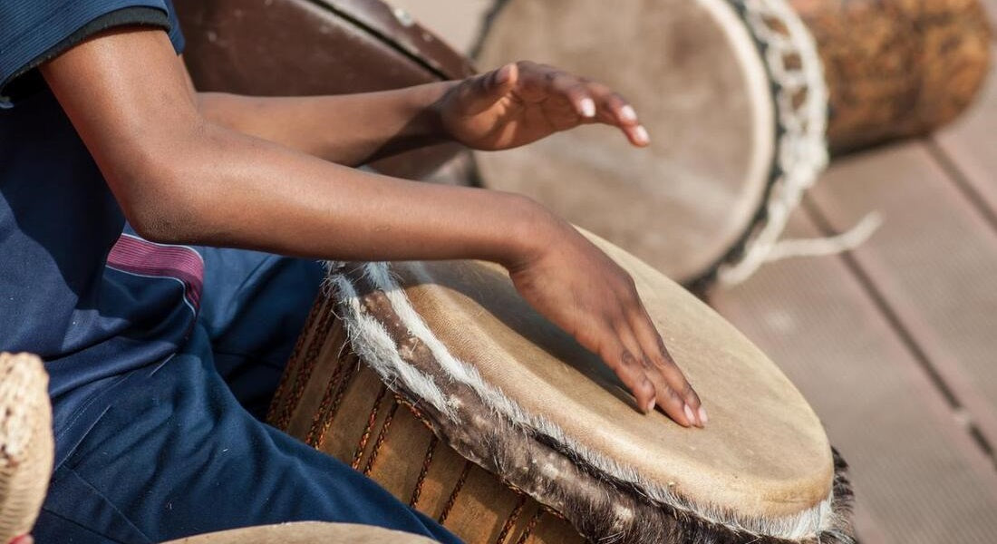 The hands of a young man playing the djembe