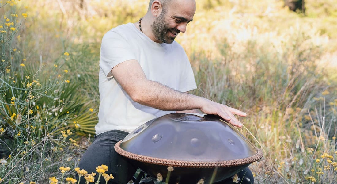 A happy handpan player in the grass
