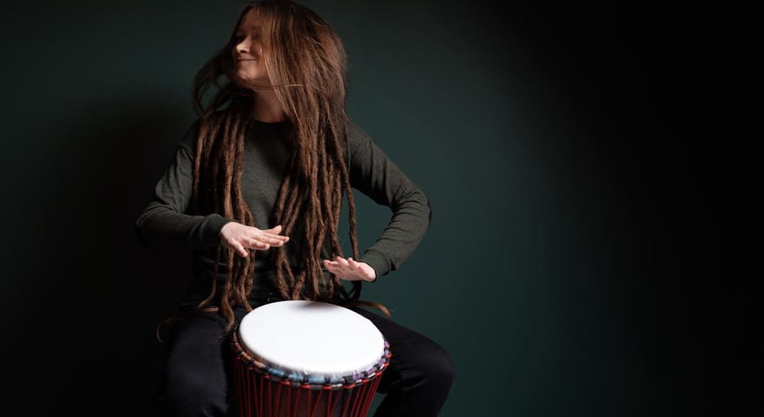 A happy woman playing the djembe