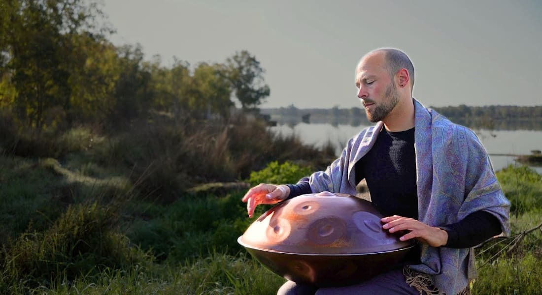 Johan Immanuel playing a Hang drum by a lake