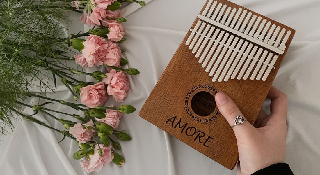 A kalimba held in a hand next to a bouquet of flowers