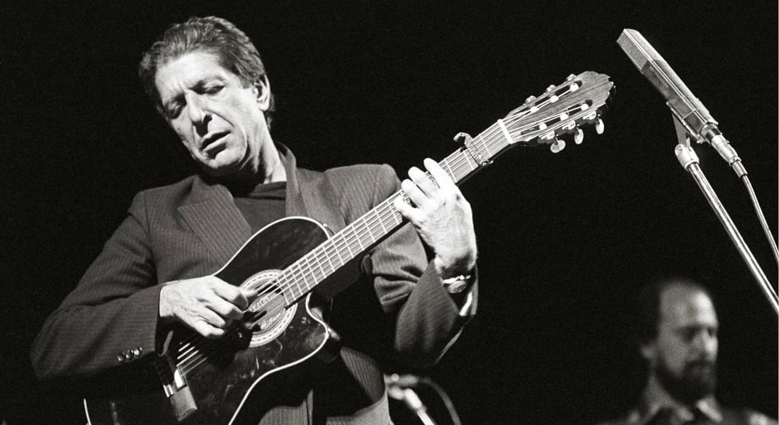 Leonard Cohen playing guitar in front of a microphone