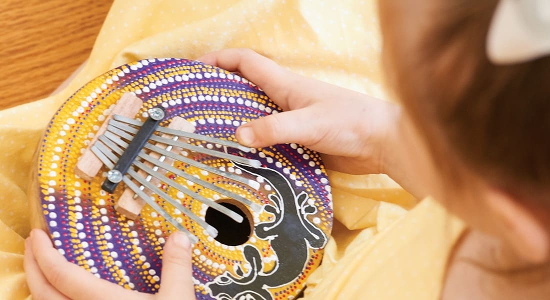 A little girl playing a coconut kalimba