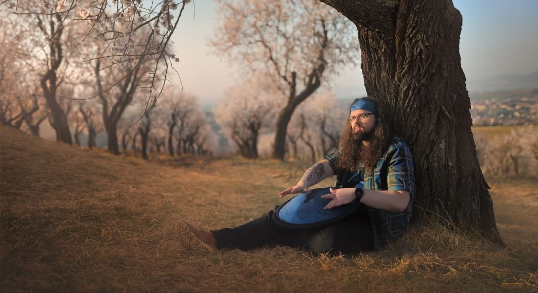 A man in the forest playing a zen drum