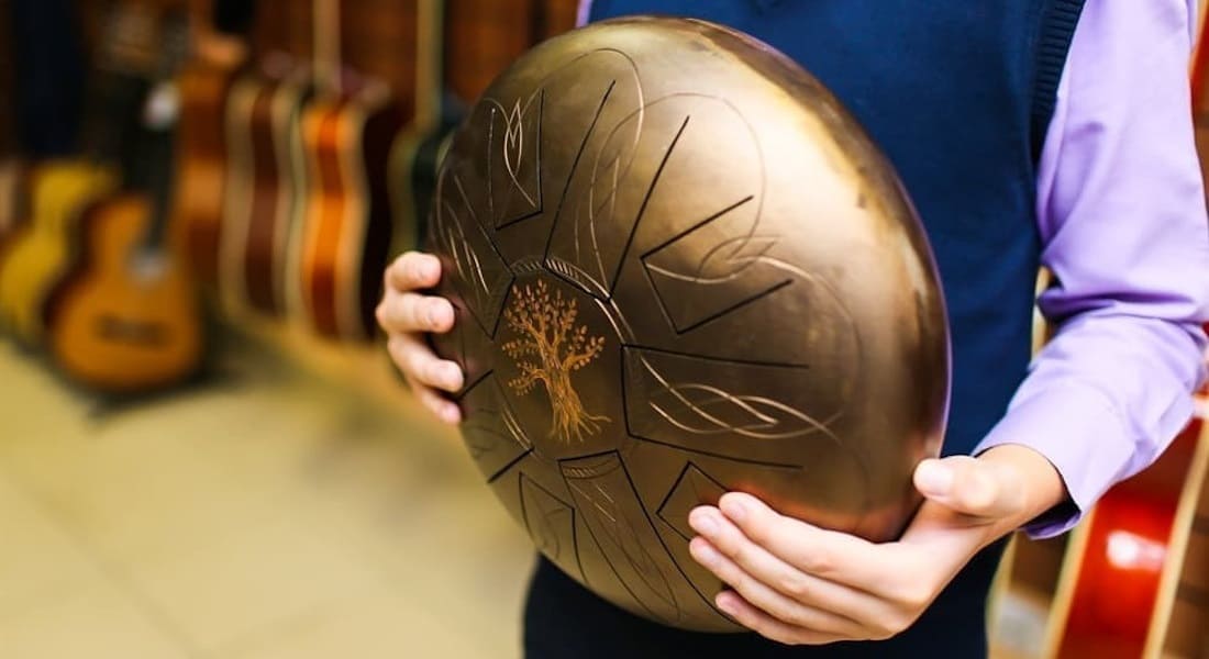 A man holding a gold tongue drum