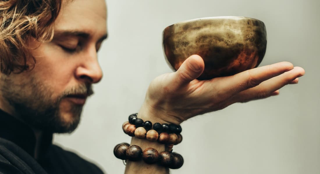 A man holding a Tibetan singing bowl in his open hand