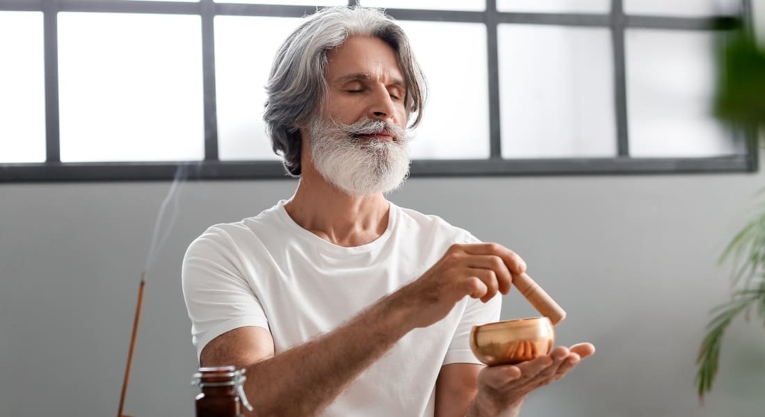 A man playing a Tibetan singing bowl with lit incense