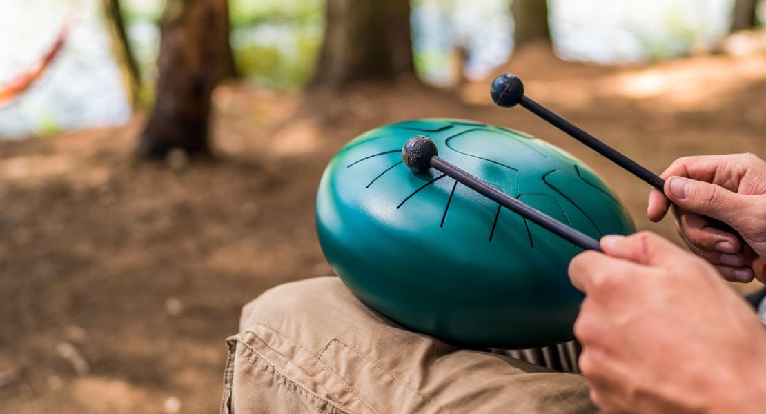A man playing a green tongue drum