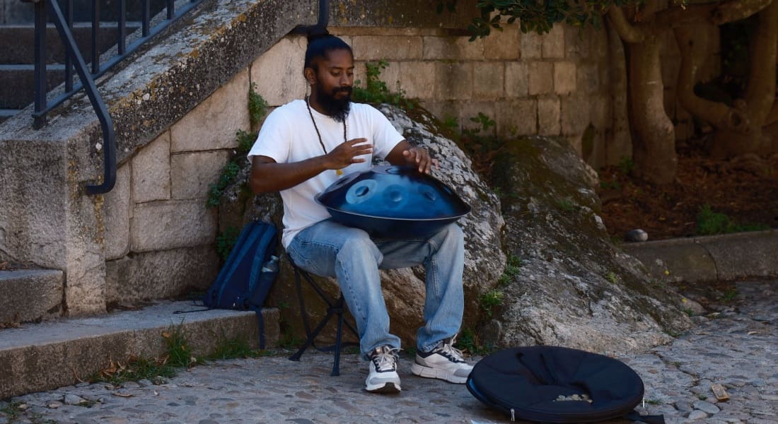 A man playing the handpan at the bottom of a staircase
