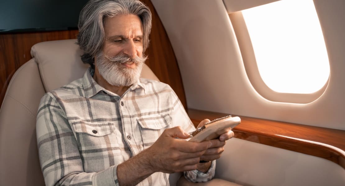 A man sitting on an airplane playing kalimba next to a window