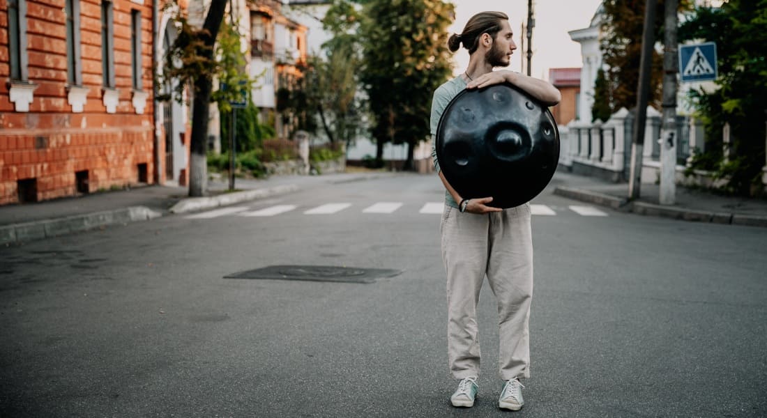A man showing a black handpan on the street