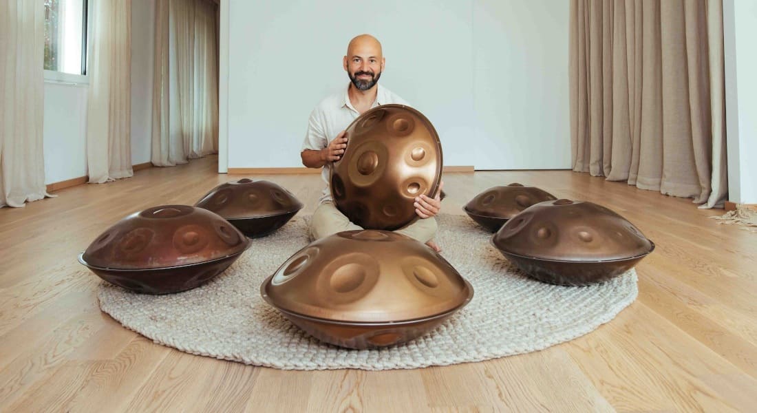 A man sitting among 5 handpans