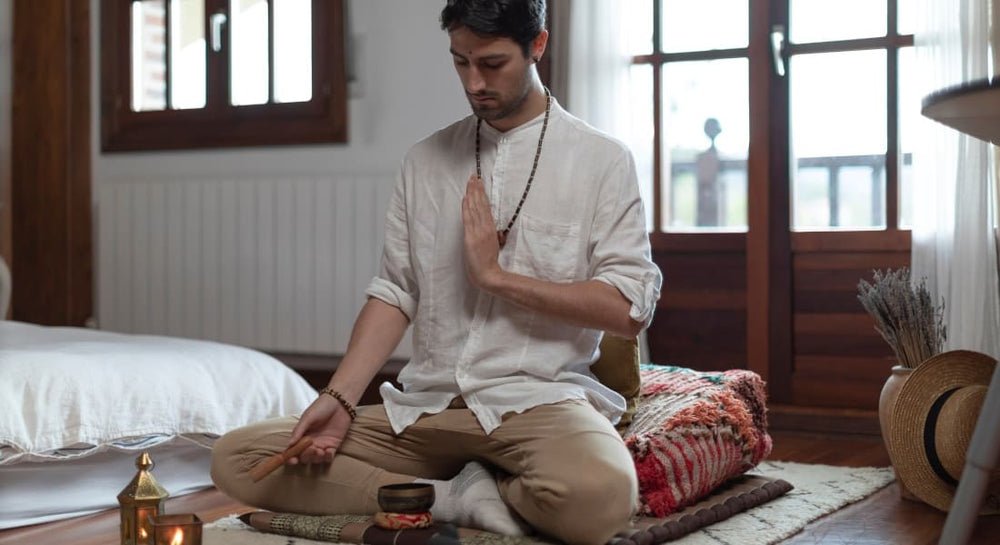 A man sitting and meditating with a small Tibetan singing bowl