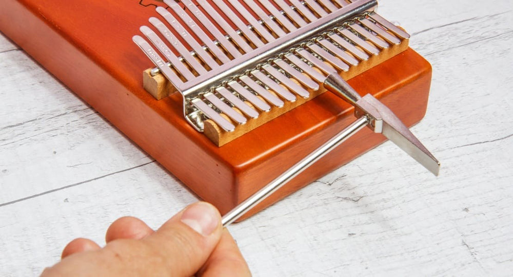 A man tuning his kalimba with a hammer