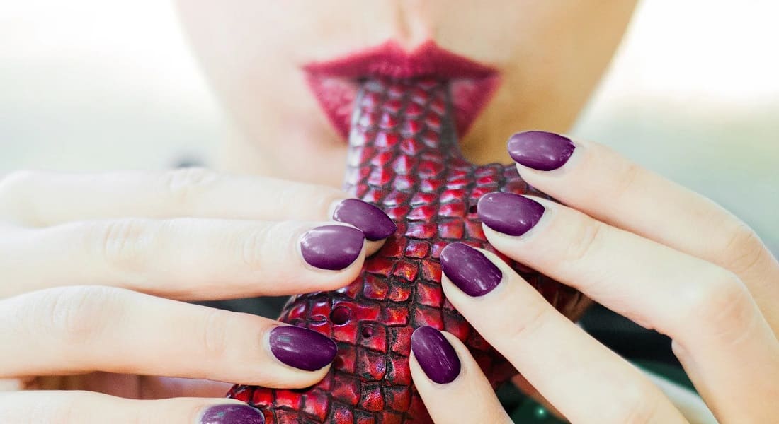 A mouth blowing into a red ocarina