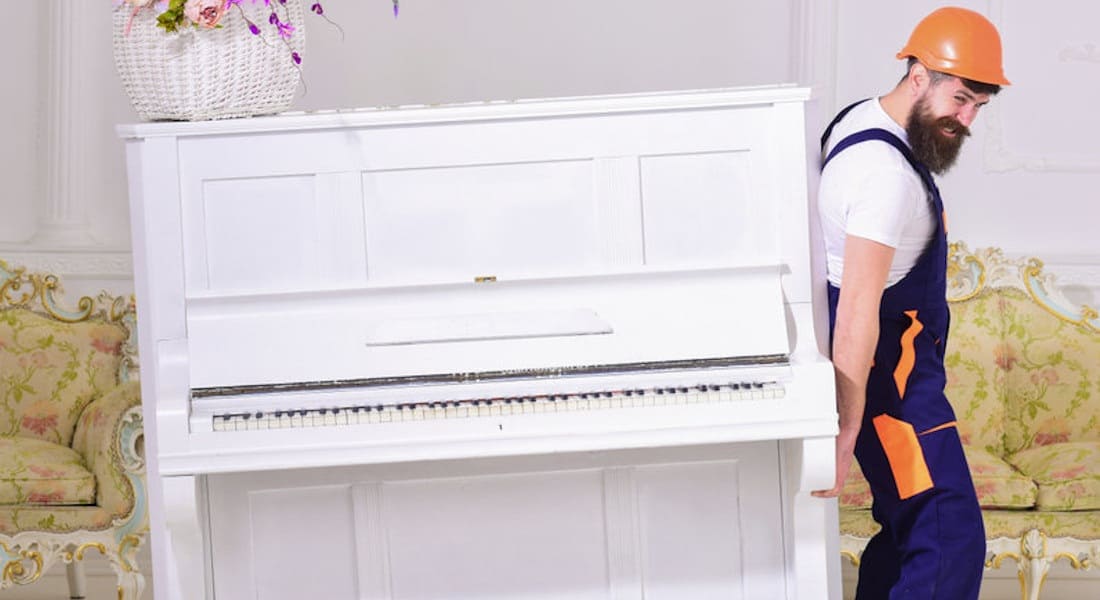 A mover lifting an upright piano