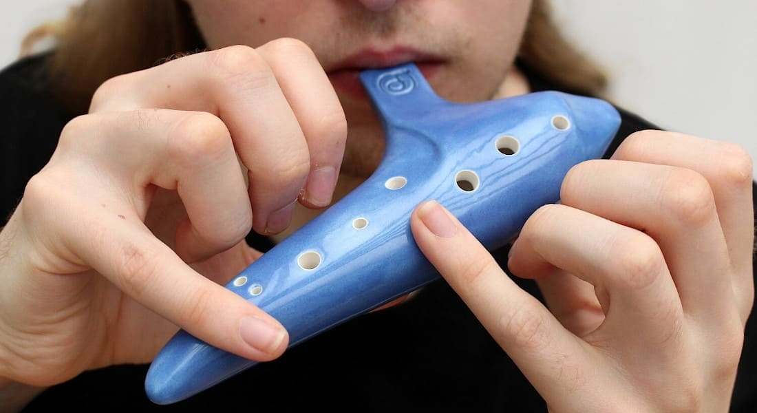 A musician placing their fingers on an ocarina