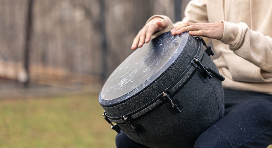 A person playing a modern djembe with tension rods