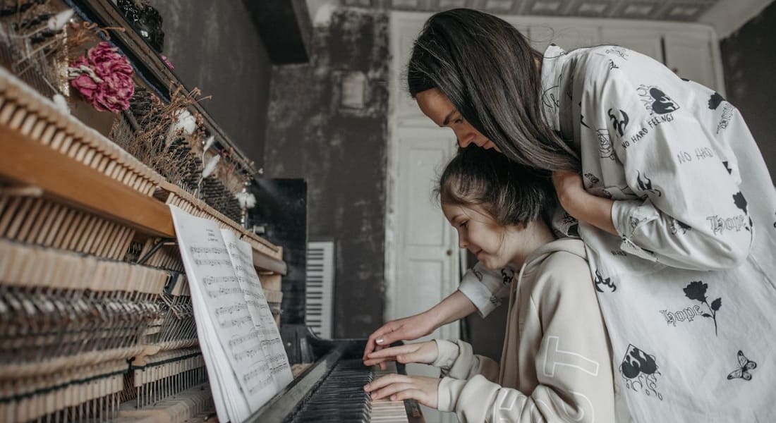 A teacher giving a piano lesson to a child