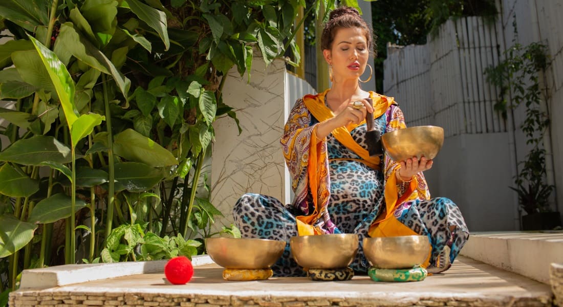 A pregnant woman playing with 4 metal singing bowls