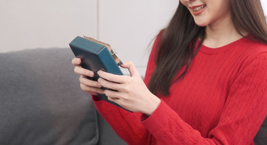 A smiling woman holding a blue kalimba